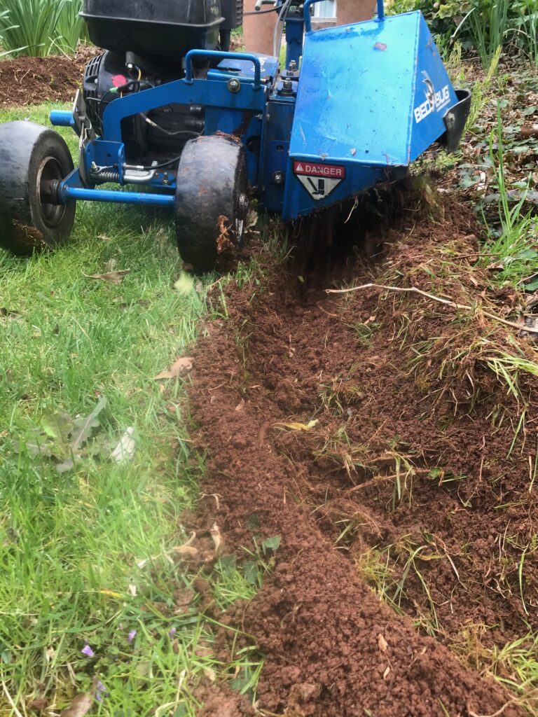 Landscaping Jobs - Landscape edging machine creating a clean trench between lawn and garden bed for professional landscape border installation. - Garden Guru Services