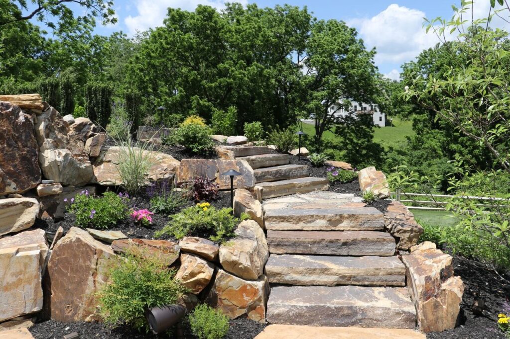 A beautiful, layered garden bed showcasing front yard landscaping design ideas with colorful flowers and shrubs. Garden Guru Services