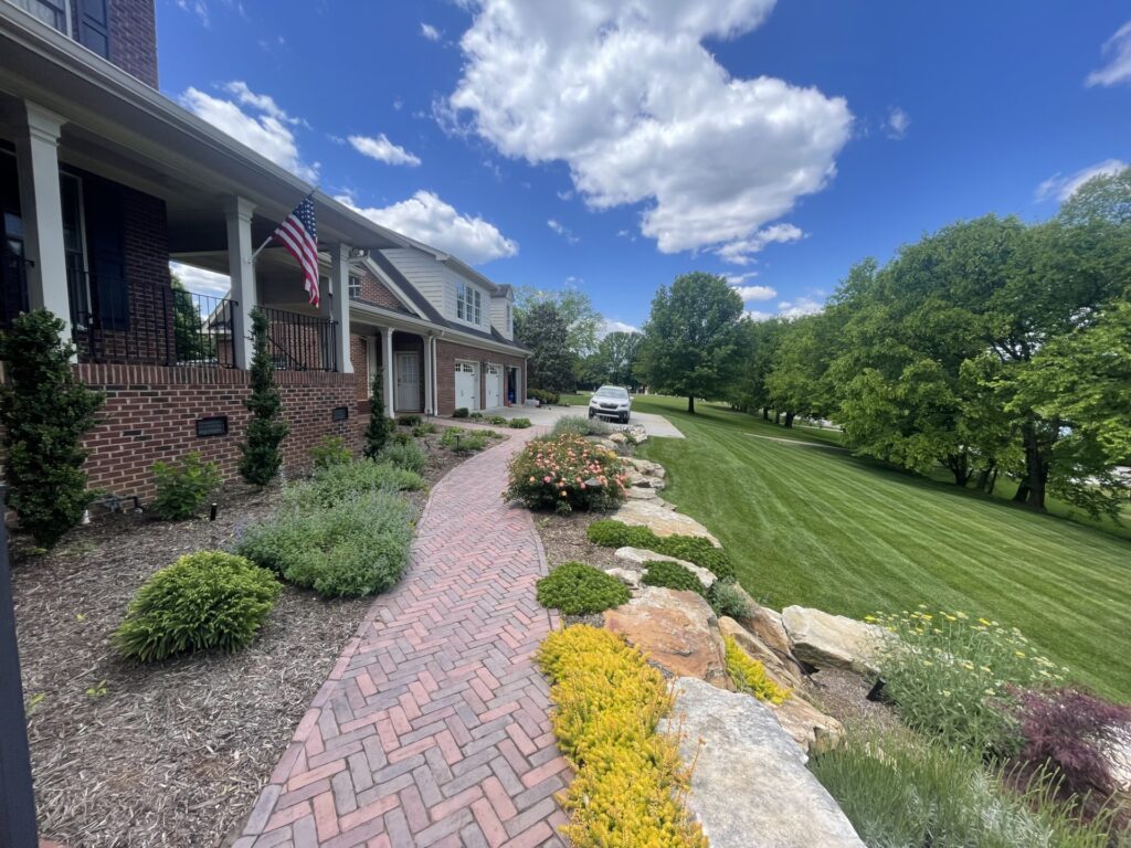 Outdoor Space - Brick walkway and natural stone rock garden with colorful shrubs, professional lawn care, and foundation landscaping design. - Garden Guru Services