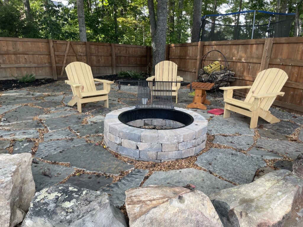 Outdoor Space - Stone block fire pit with flagstone patio and seating area for backyard outdoor living space design. - Garden Guru Services